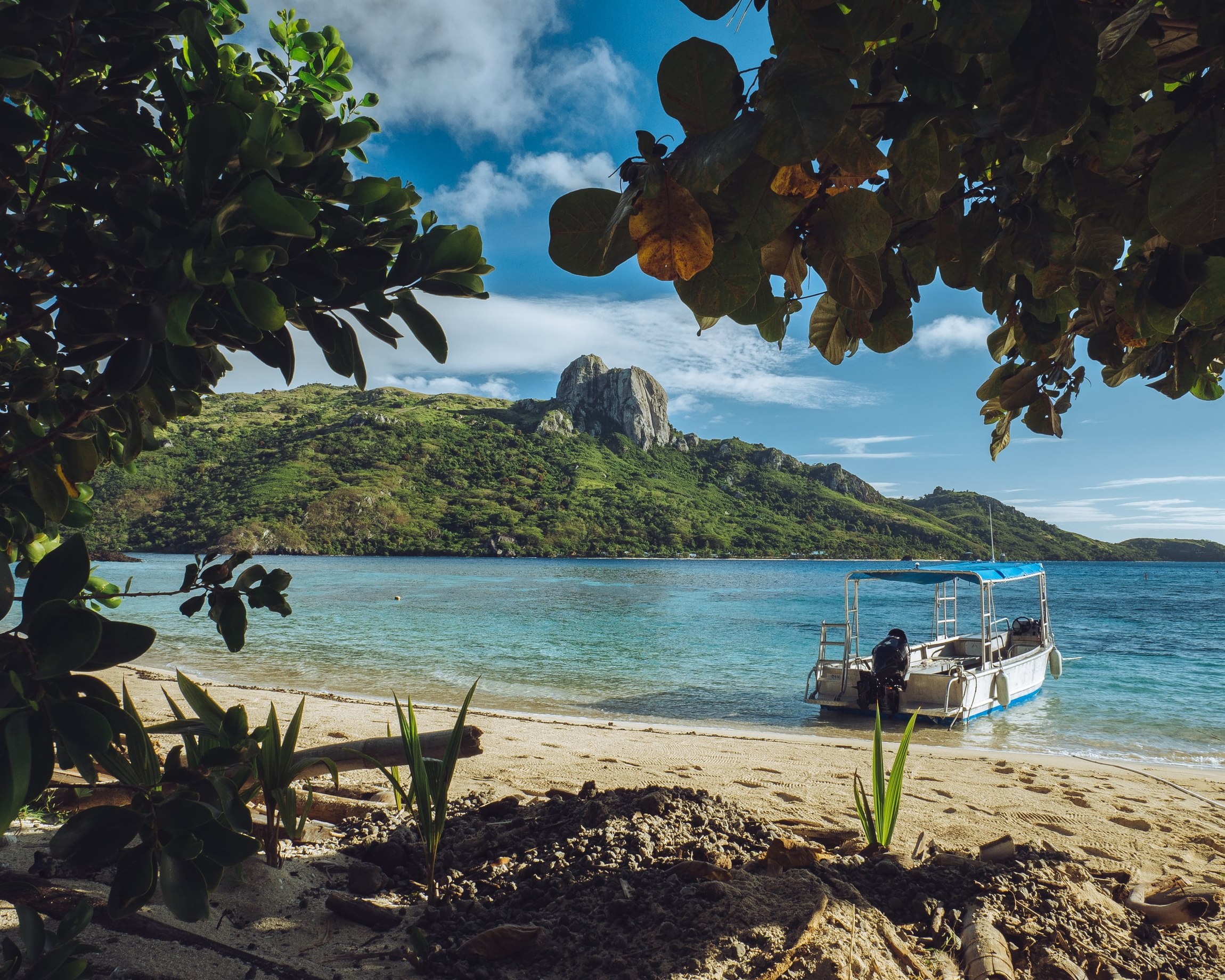 Strand mit Boot und Bergen im Hintergrund