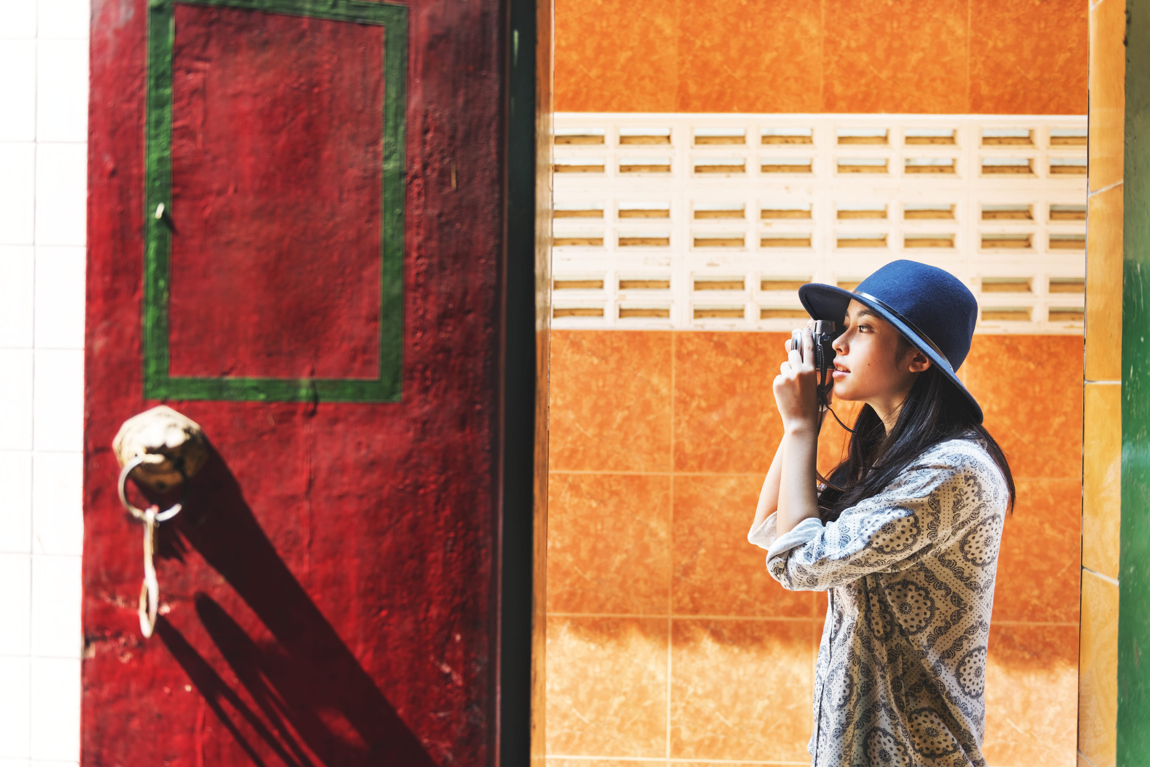 Frau steht vor einer bunter Häuserwand und schießt Fotos