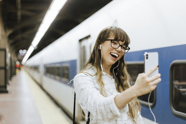 Junge Frau macht ein Selfie vor einem Zug