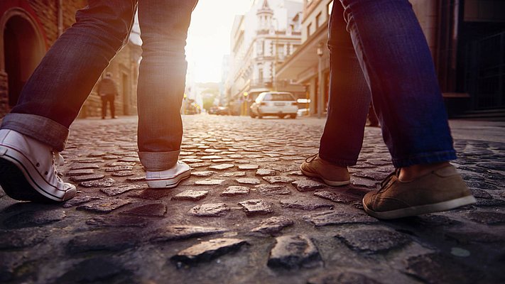 2 Personen gehen auf einem gepflasterten Weg, man sieht nur die Beine