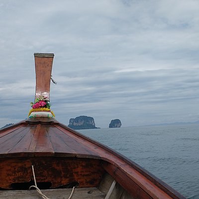 Blick vom Bug eines Holzbootes auf das Meer mit zwei kleinen Felseninseln am Horizont.