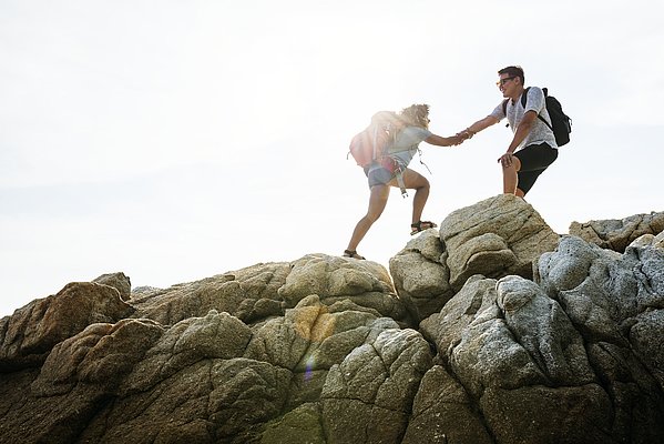 Zwei junge Menschen klettern auf einem Felsen