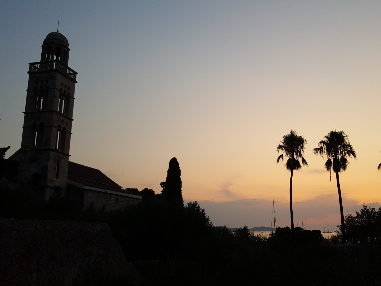 Kirchenturm und Palmen vor Sonnenuntergang