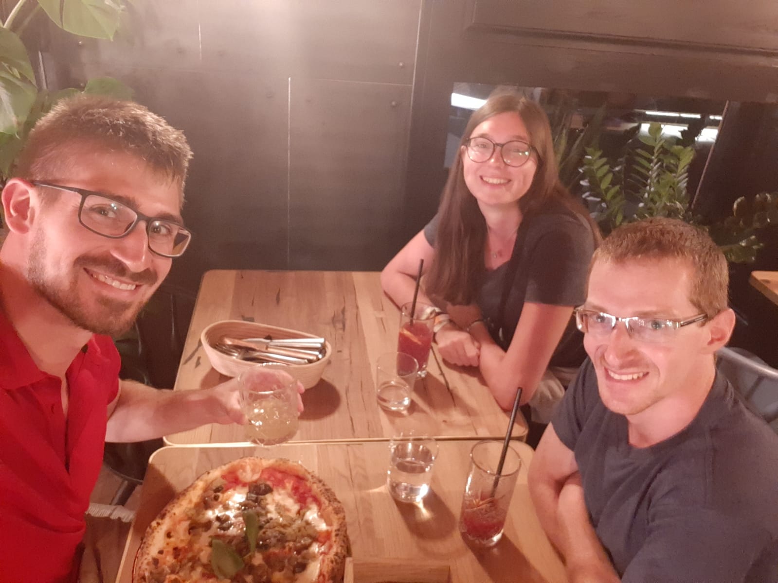 drei Personen am Tisch mit Pizza